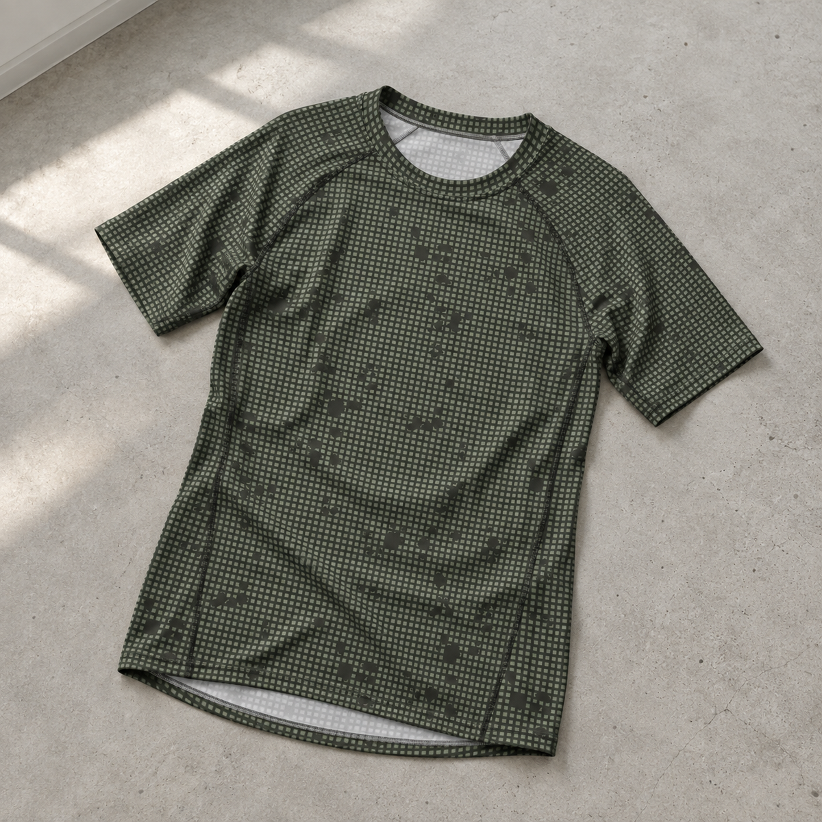 Desert Night Camo SS Rash Guard laid on a pale-gray concrete floor
